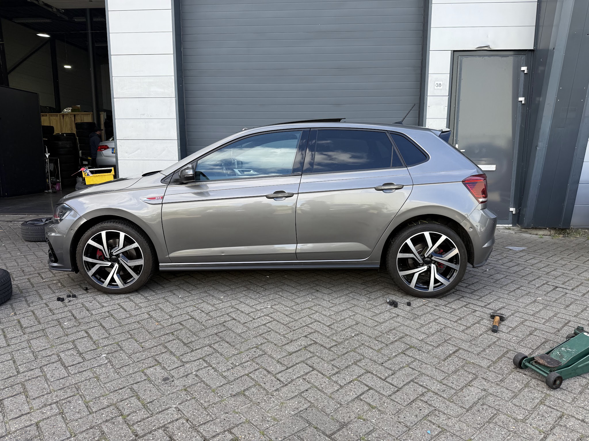 Een grijze Volkswagen Polo voor de deur van Q-Banden terwijl de wielen gewisseld worden