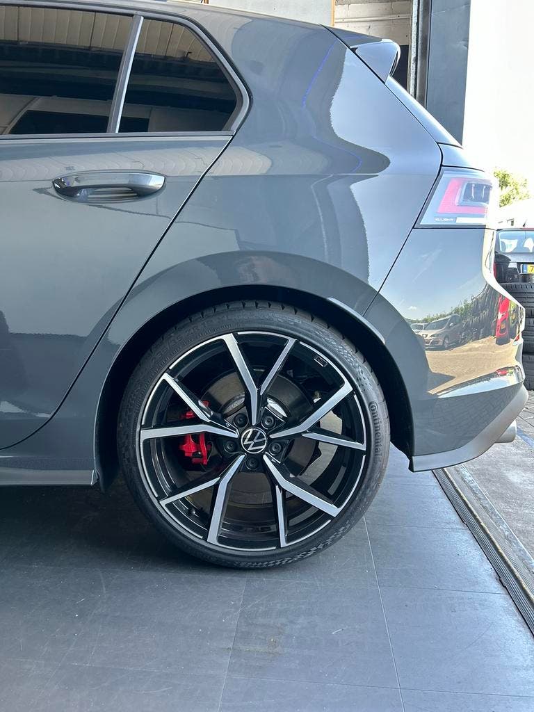 Het achterwiel van een grijze Volkswagen Golf met rode remklauwen